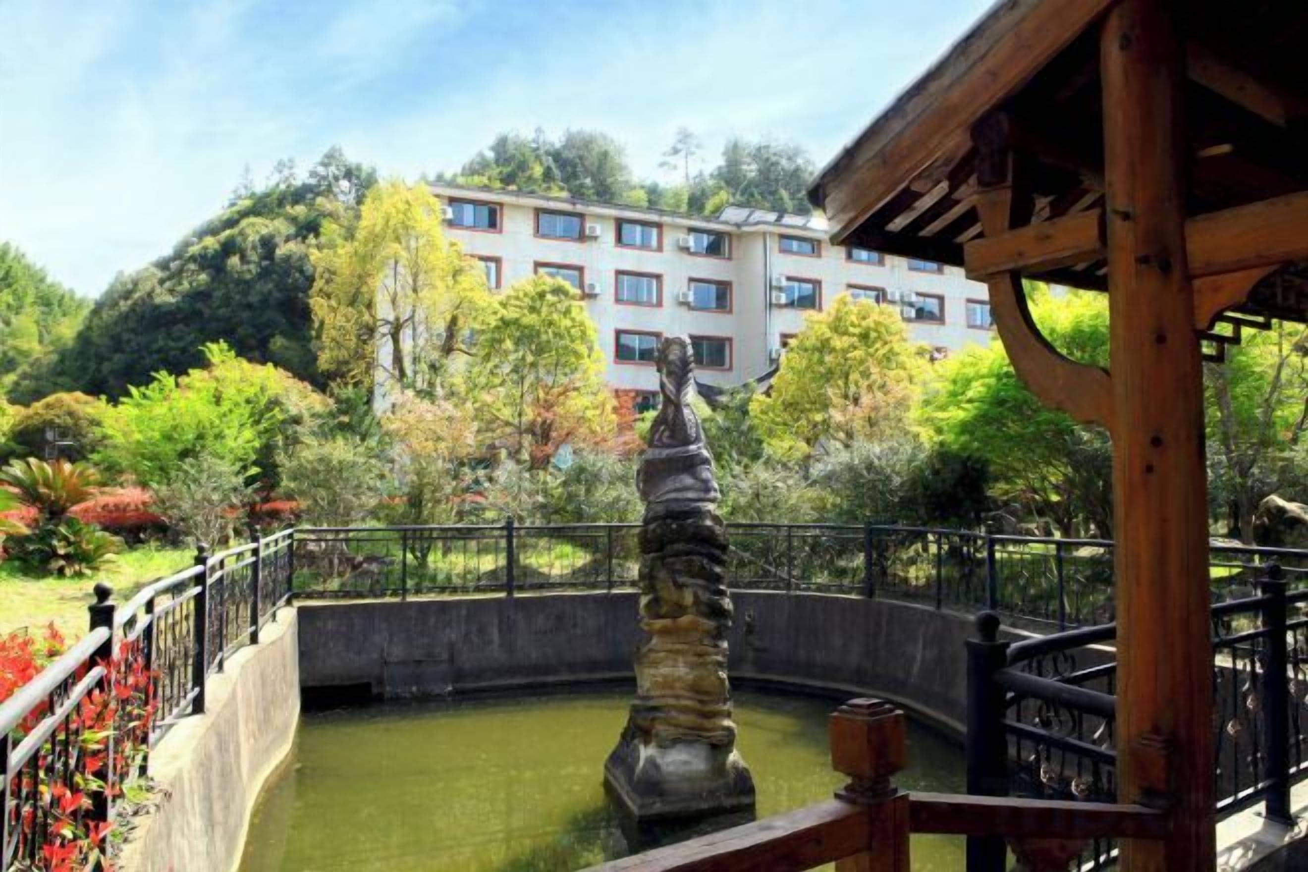 A courtyard with a fountain, a wooden pergola, and a building in the background.