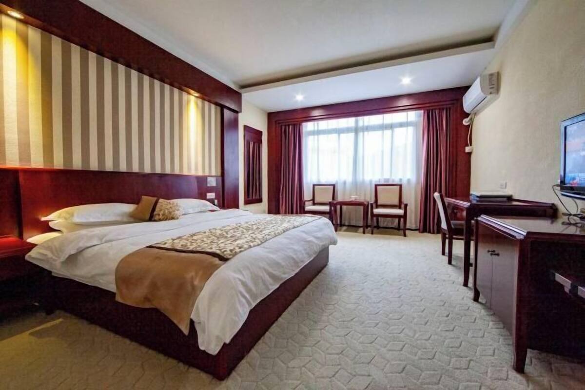 A hotel room with a large bed, a desk, a chair, and a television.