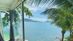 Una habitación con un amplio ventanal que da a una masa de agua y un paisaje montañoso.