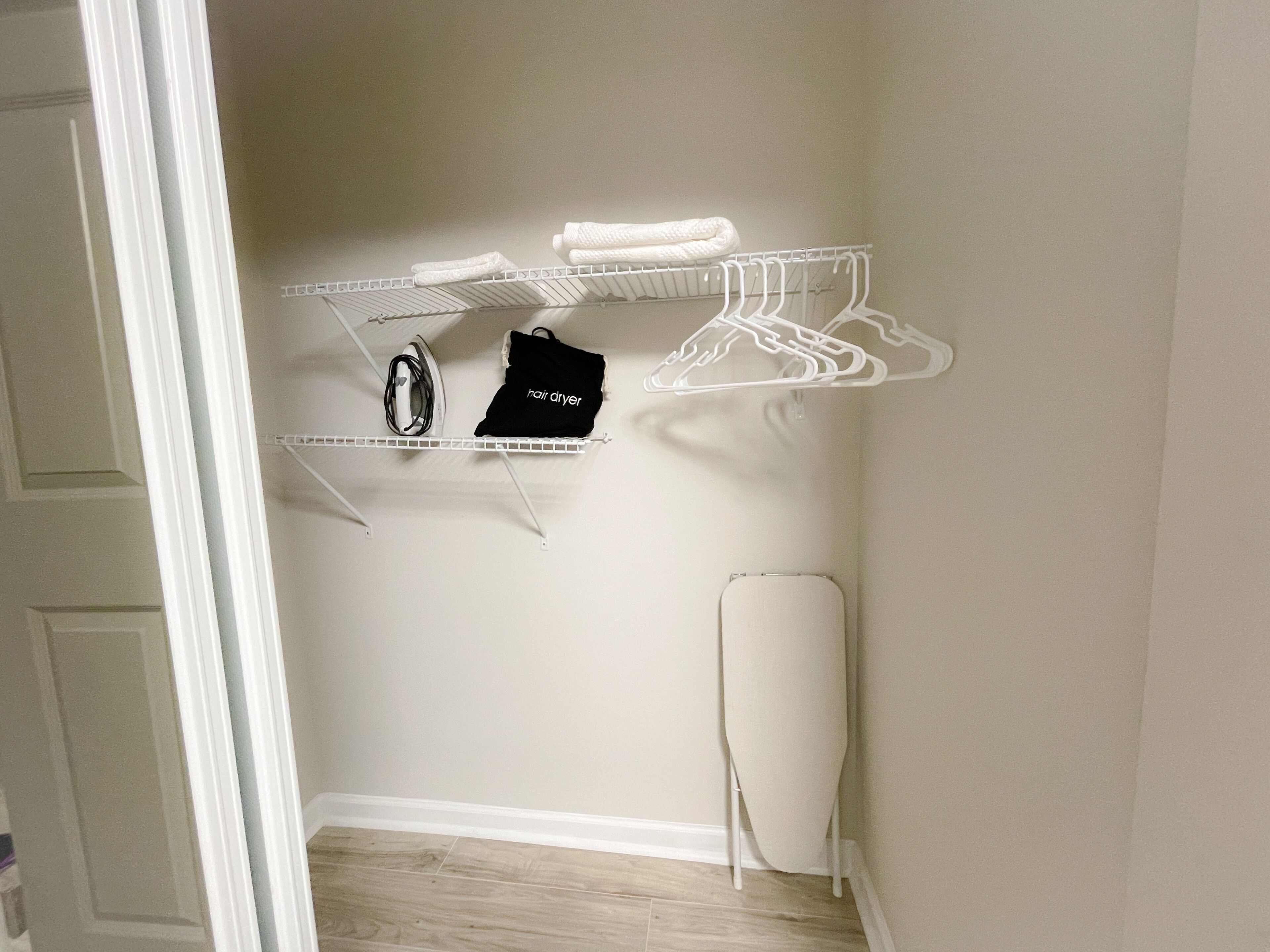 A closet with shelves, a hanging rack, and a hair dryer.