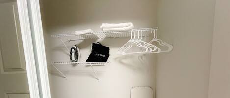 A closet with shelves, a hanging rack, and a hair dryer.