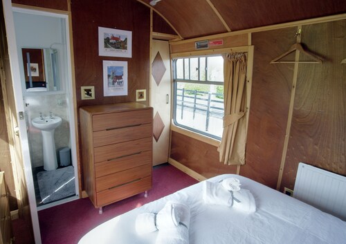 A carefully converted  heritage railway coach in the countryside.