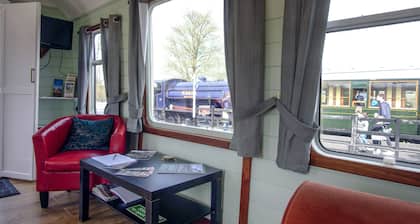 A carefully converted heritage railway coach in the countryside.