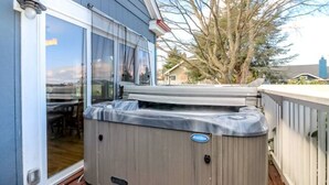 Un jacuzzi en una terraza de madera con una puerta de vidrio que da a un patio.