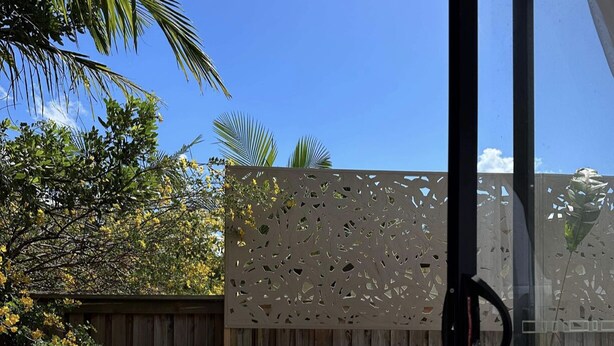 Eine Holzterrasse mit einer Glastür, die zu einer Patio führt.