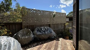 Eine Holzterrasse mit dekorativer Abdeckung, einer Glastür und einem Holzzaun.