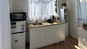 Eine kleine Küche mit Mikrowelle, Spüle und kleinem Kühlschrank.