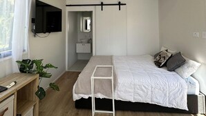 Ein modernes Schlafzimmer mit einem Bett, einem Nachttisch und einem an der Wand montierten Fernseher.