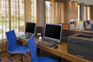 Zona de treball d'hotel amb dues taules, cadascuna amb un ordinador i teclat, i una impressora.