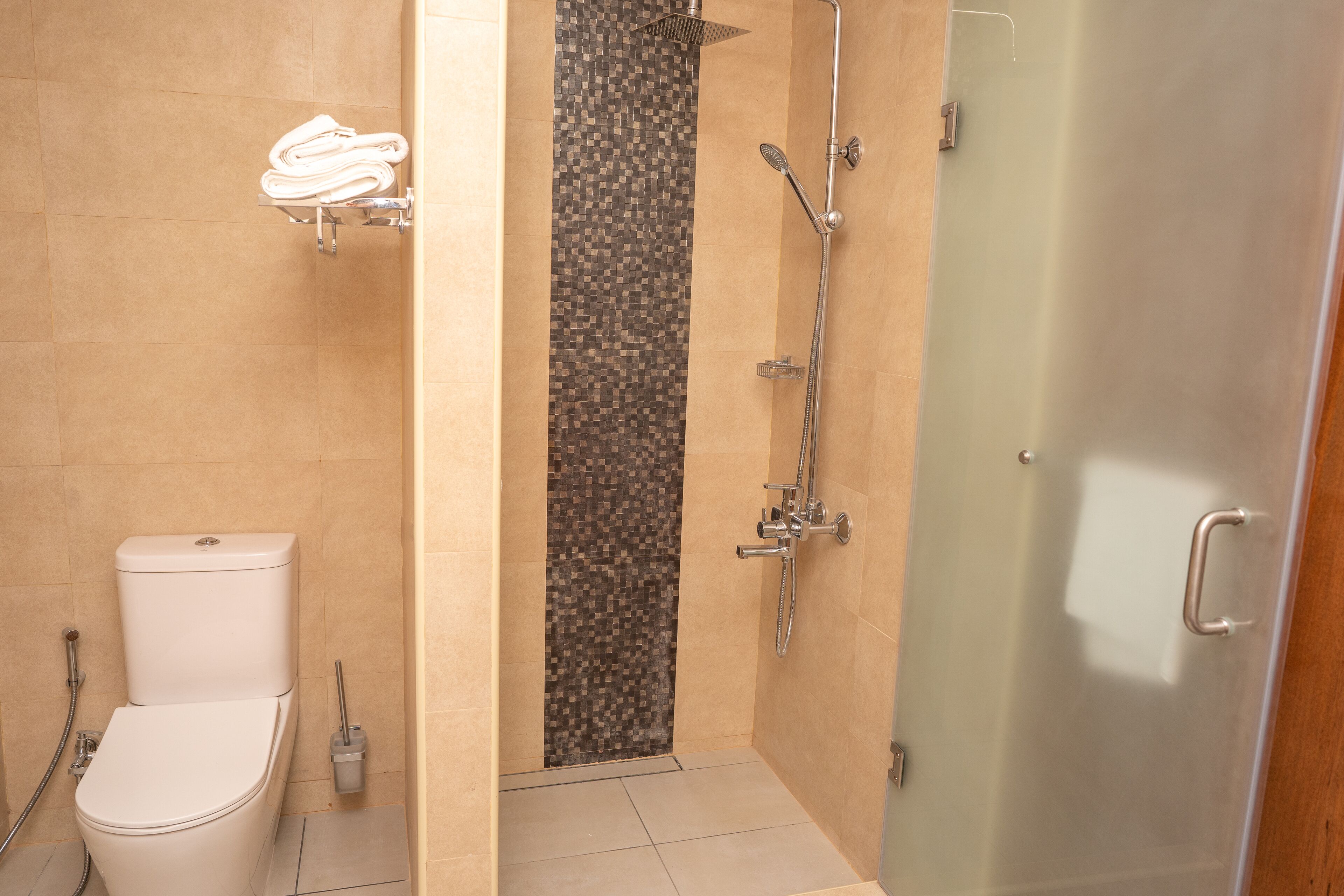 Une salle de bain comprenant des toilettes, une douche avec une porte en verre et un porte-serviettes.