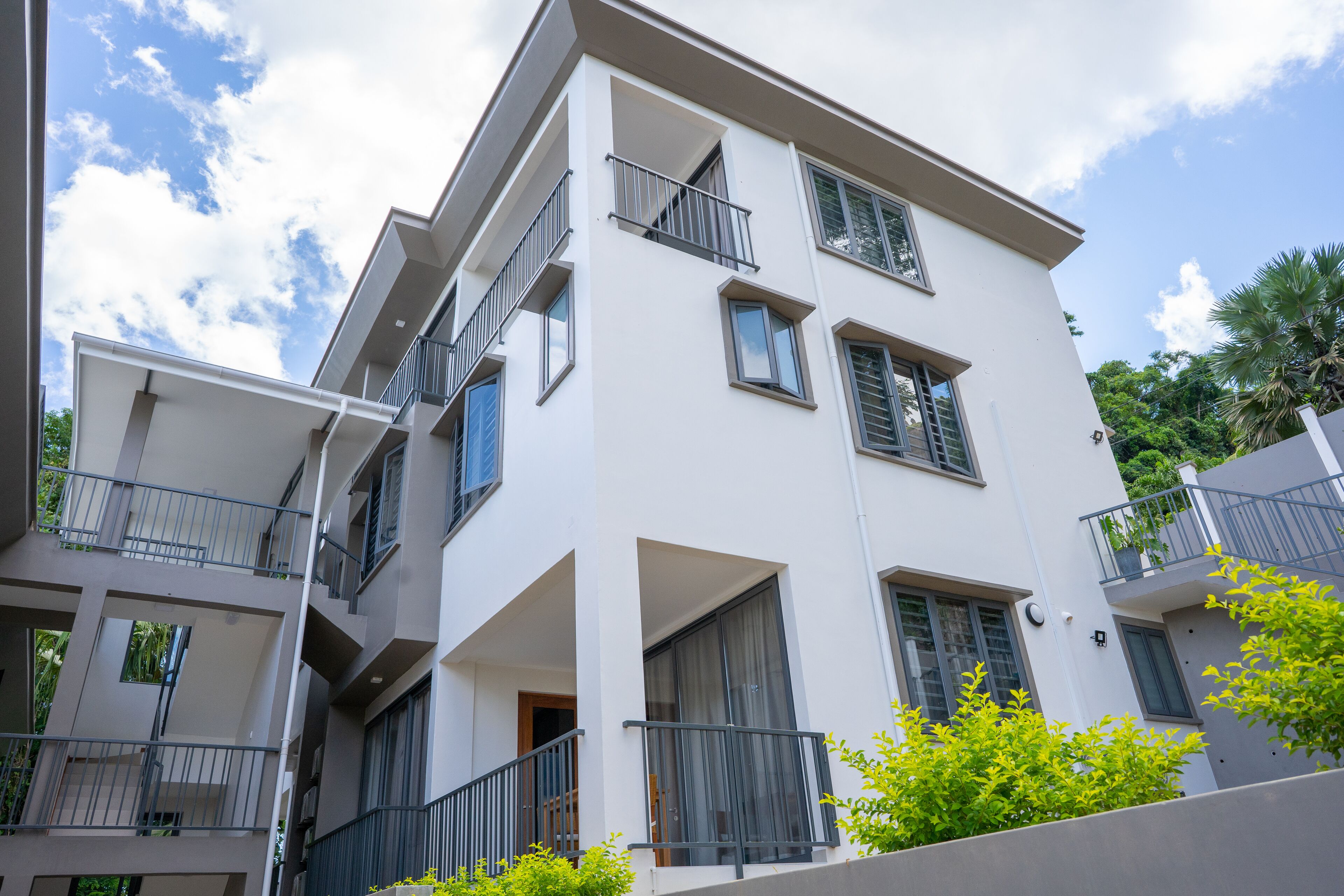 Ein mehrstöckiges Wohngebäude mit Balkonen, großen Fenstern und einer weißen Fassade.