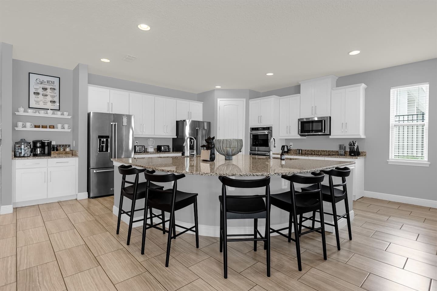 A modern kitchen with white cabinets, stainless steel appliances, and a central island with bar stools.