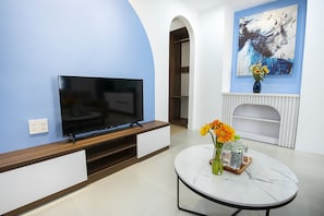 Relax in this stylish living room with a flat-screen TV, round table, and beautiful artwork.