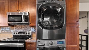 Eine Küche mit Mikrowelle aus Edelstahl, Backofen und einem übereinander angeordneten Wascher-Trockner.