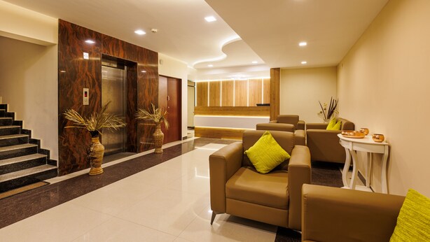 Een moderne lobby met een receptiebalie, een zithoek en liften.