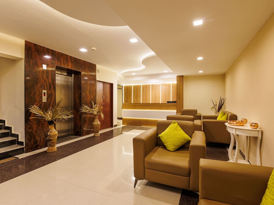 Een moderne lobby met een receptiebalie, een zithoek en liften.