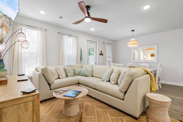 A modern living room with a sectional sofa, a round coffee table, and a ceiling fan.