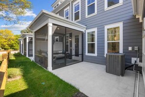 A two-story house with a covered patio area, a visible air conditioning unit, and a well-maintained lawn.