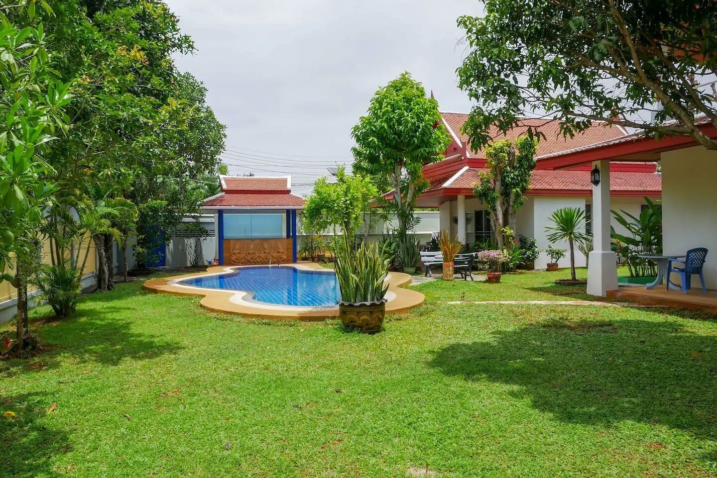 A residential property with a swimming pool, a covered patio, and a well-maintained lawn.