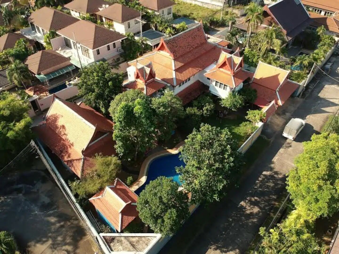 An aerial view of a residential area with multiple houses, a swimming pool, and a street.