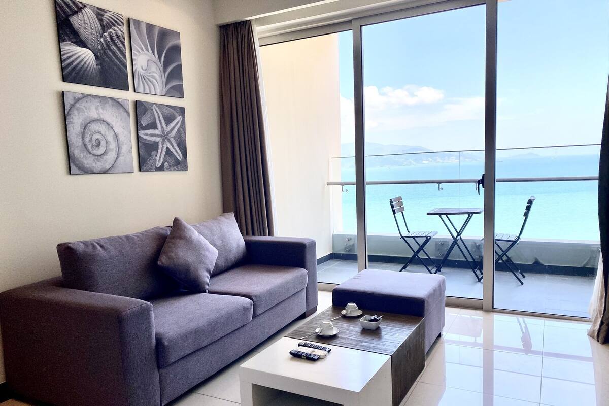 A modern living room with a grey sofa, a white coffee table, and artwork on the wall.