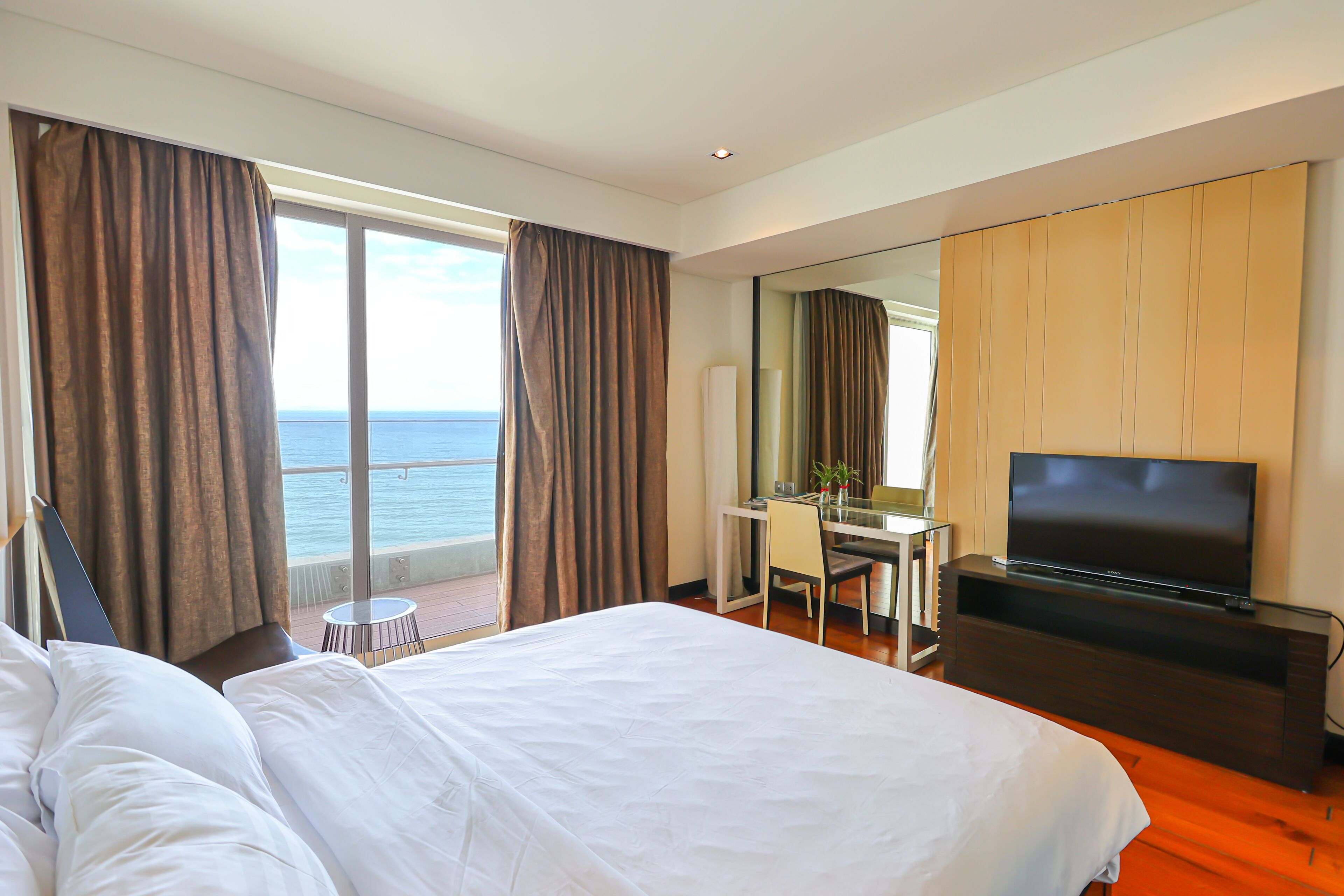 Una habitación de hotel con una cama grande, un escritorio, un televisor y vista al mar.