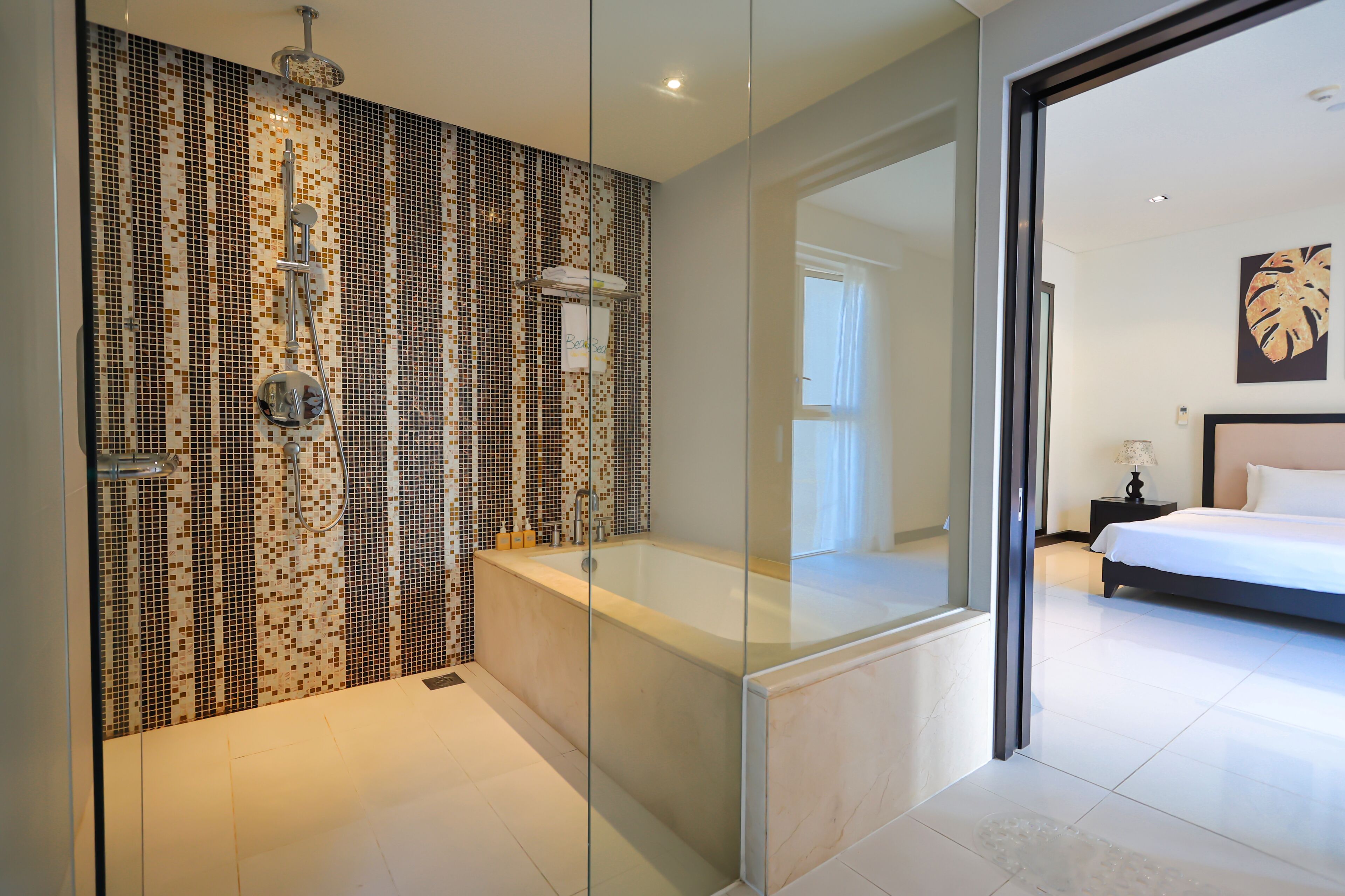 A modern bathroom with a glass-enclosed shower, a large bathtub, and a tiled mosaic wall.