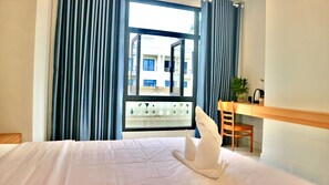 Een hotelkamer met een bed, een bureau, een stoel en een raam met gordijnen.