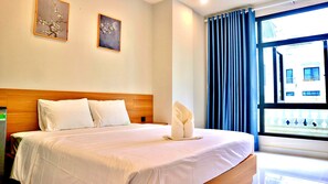 Hotelkamer met een bed, twee kussens, een nachtkastje en een raam met gordijnen.