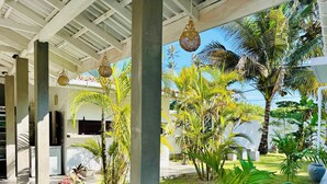 A covered outdoor area with concrete pillars, hanging lights, and a well-maintained lawn with palm trees. - The White House Villa (Ahangama)