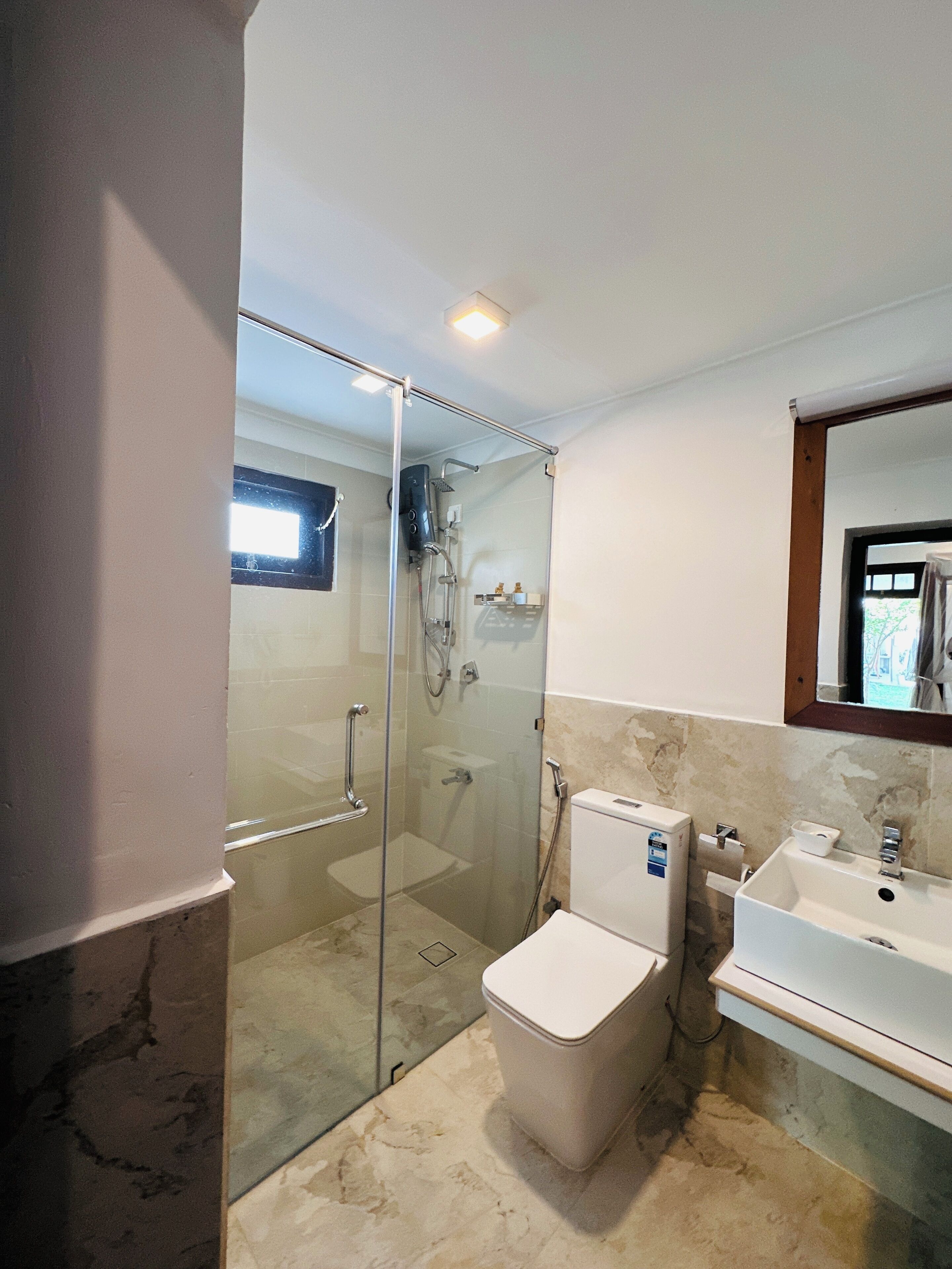Un baño moderno con ducha envuelta en vidrio, inodoro y lavabo.