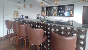A bar area with a polka dot marble countertop, brown leather bar stools, and hanging spherical pendant lights. - The Aryan Hotel Gangtok (Gangtok)