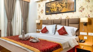 A hotel room with a large bed, a wooden headboard, two bedside lamps, a telephone, and a painting on the wall. - The Aryan Hotel Gangtok (Gangtok)
