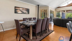 Un comedor con una mesa dispuesta para seis personas, rodeada de sillas, en una habitación con un ventanal y vistas a la vegetación.
