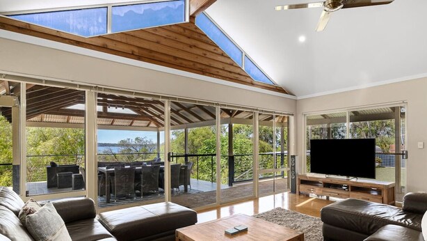 Una sala de estar moderna con un televisor grande, asientos cómodos y vistas al exterior.