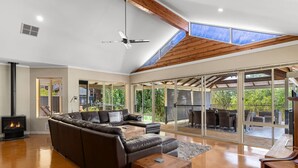 Un salón amplio con un sofá modular, una chimenea y un gran ventanal corredera que da a un espacio exterior.