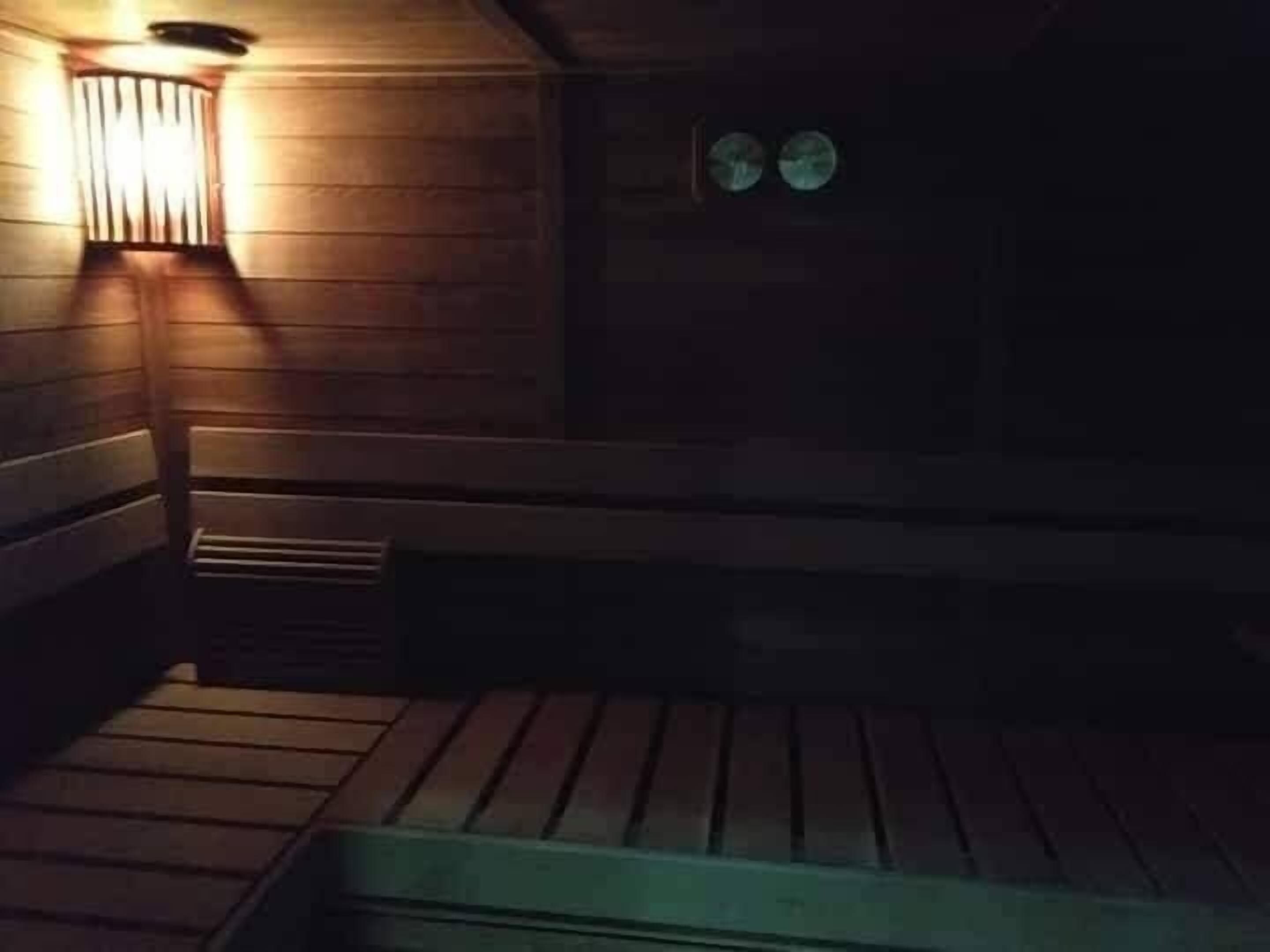 L'intérieur d'un chalet en bois, avec un banc et un luminaire fixé au mur.