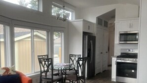 A spacious living room with a dining area, a kitchen, and large windows.
