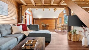 A cozy living room with a sofa, a coffee table, and a dining area.
