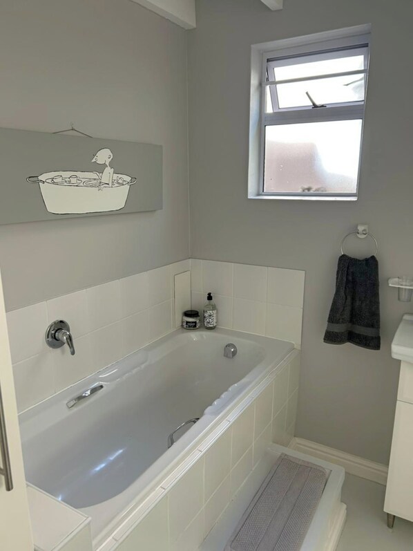 A modern bathroom with a freestanding bathtub, a window, and a towel rack.