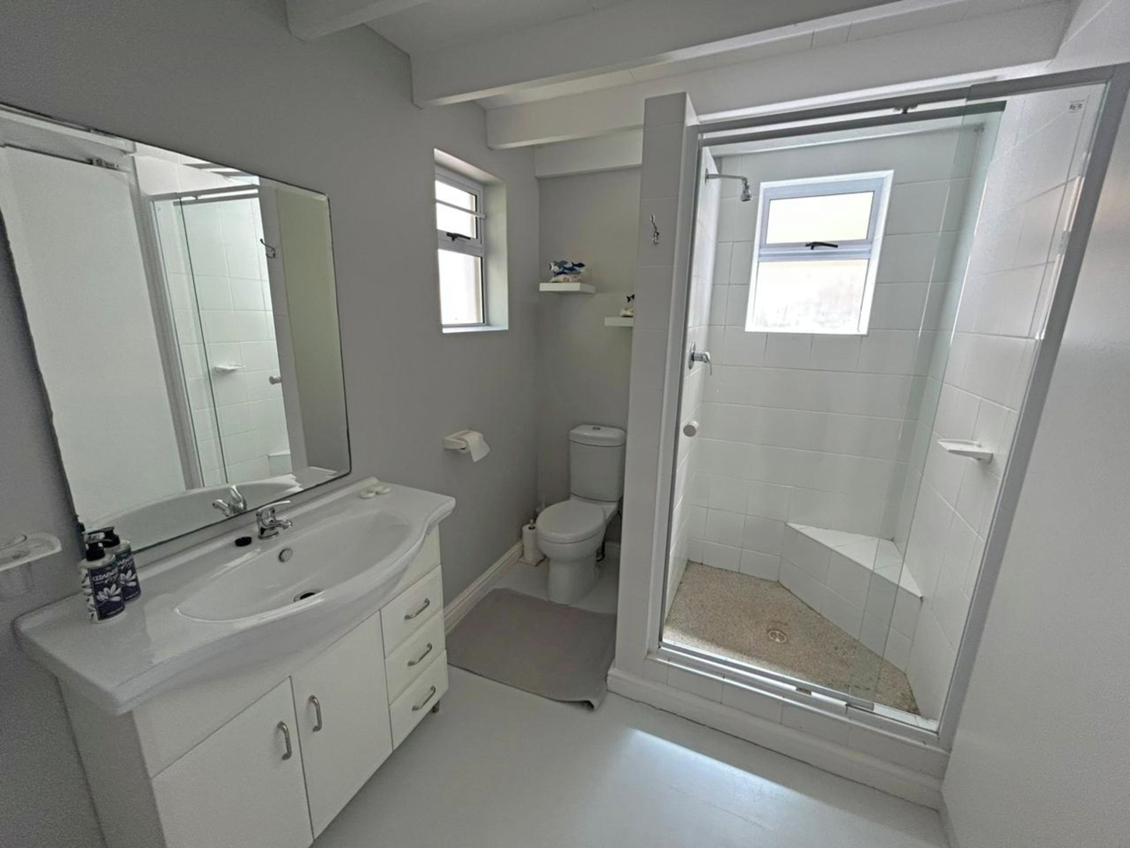 Ein modernes Badezimmer mit großem Spiegel, Waschbecken, Toilette und Dusche.