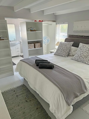 A bedroom with a bed, bedside tables, a wardrobe, a mirror, and a window.