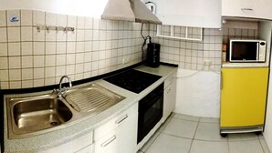 A compact kitchen with a sink, stove, oven, and a microwave. - 80sqm two-room apartment - Wipfelder Montuerzimmer (Wipfeld)