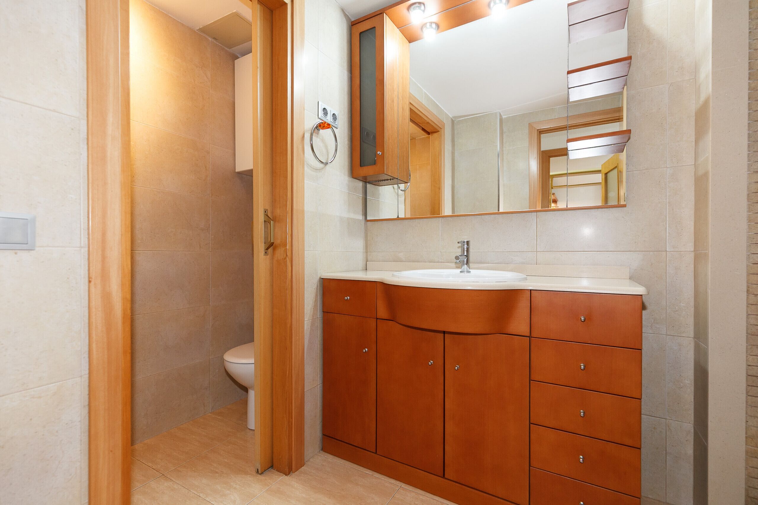 Un bagno con un mobile bagno in legno, un lavandino e un water.