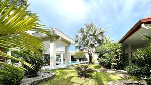 A well-maintained garden with a pool, palm trees, and a stone pathway.