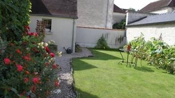 A garden with a white building, a small window, and a table with chairs.