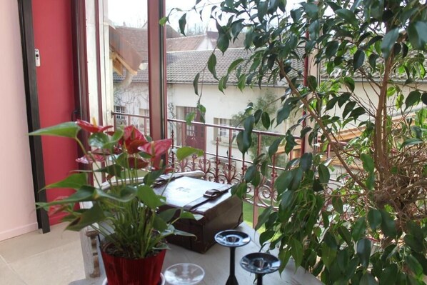 A balcony with a potted plant, a suitcase, and a small table with a tray.