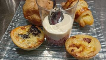 A glass plate with pastries and a dessert on a reflective surface.