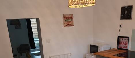 A modern kitchen with a dining table, chairs, a pendant light, and a sign on the wall.