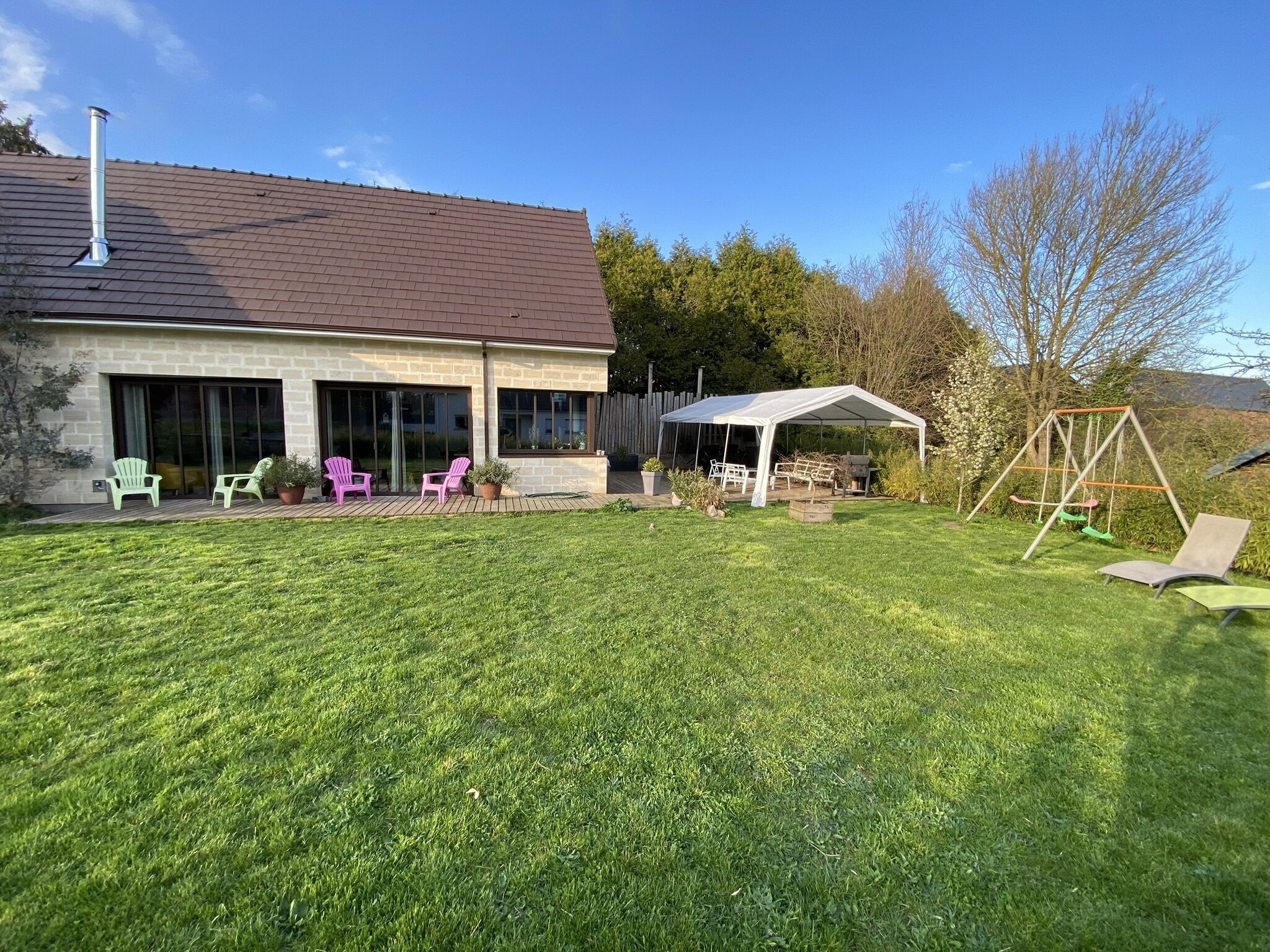 Une maison dotée d’un patio couvert, d’un espace salon extérieur et d’une balançoire.